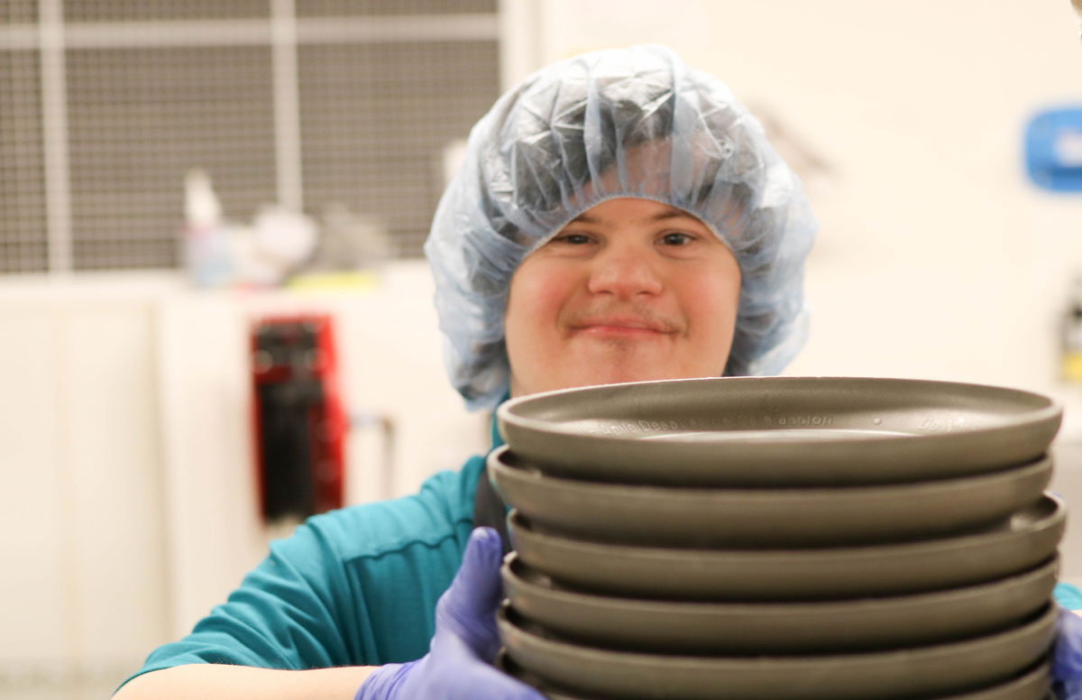 Anthony proudly holding a stack of plates