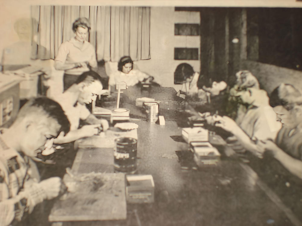 black and white photo of people at work around a table