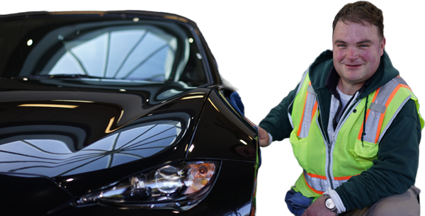 Work Opportunities client proudly sitting beside a car he is servicing at work